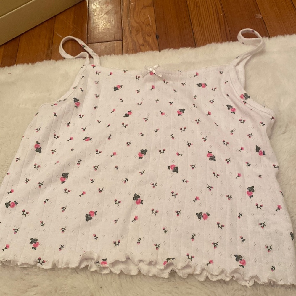 A white tank top with pink flowers on it